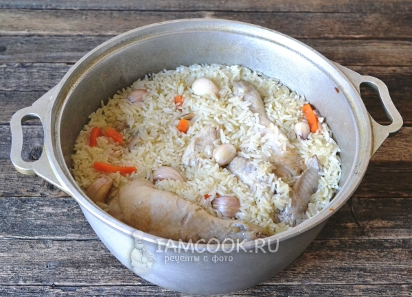 Pripravljen pilaf iz parjenega riža s piščancem v kotlu